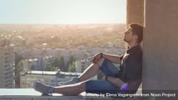 Man sitting and relaxing atop roof 47G7B4