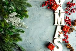 Wintry pine branch and holly with "XMAS" letters on side of grey background