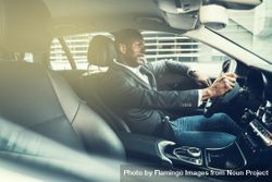 Man in business attire driving luxury vehicle 56Wne4