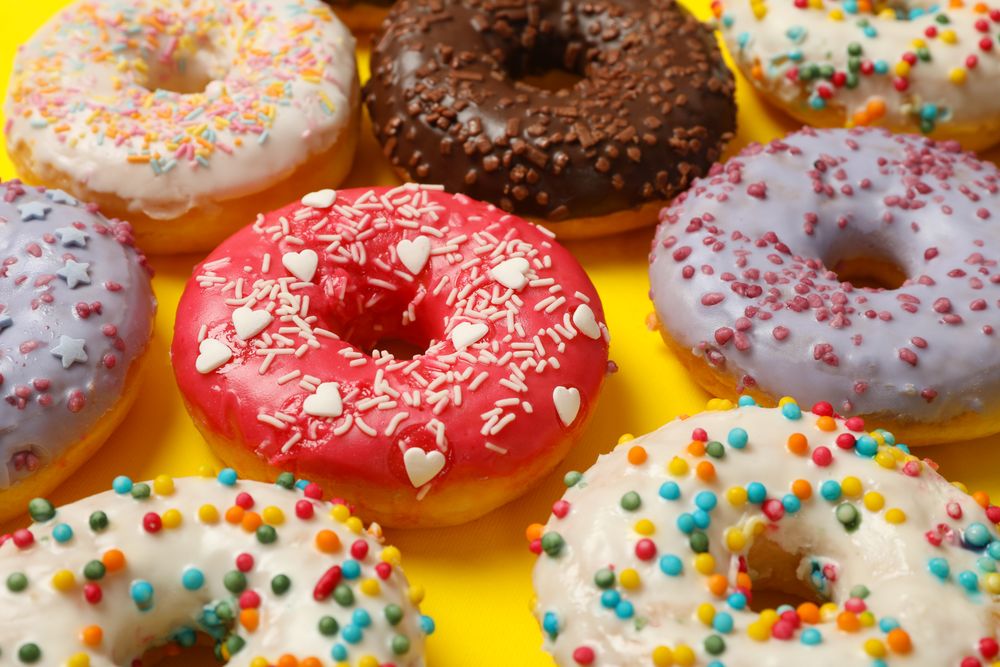 Flat lay with tasty donuts on yellow background