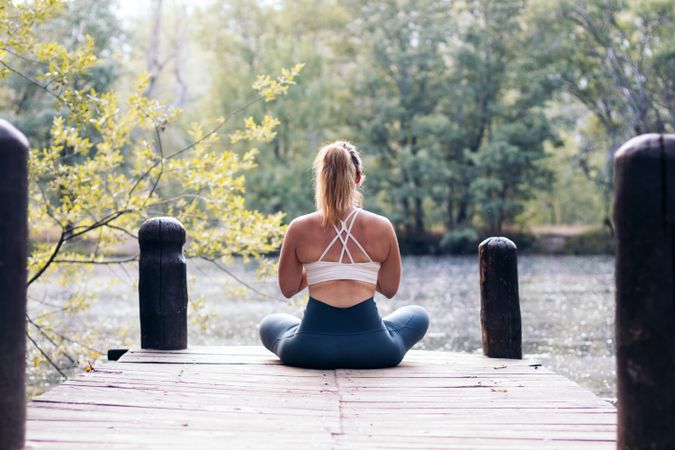 Woman meditating in nature near a lake