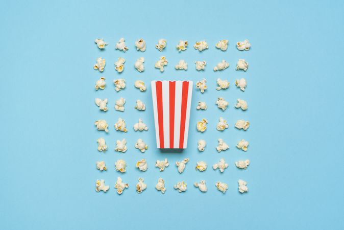 Popcorn flakes and striped box flat lay on a blue background