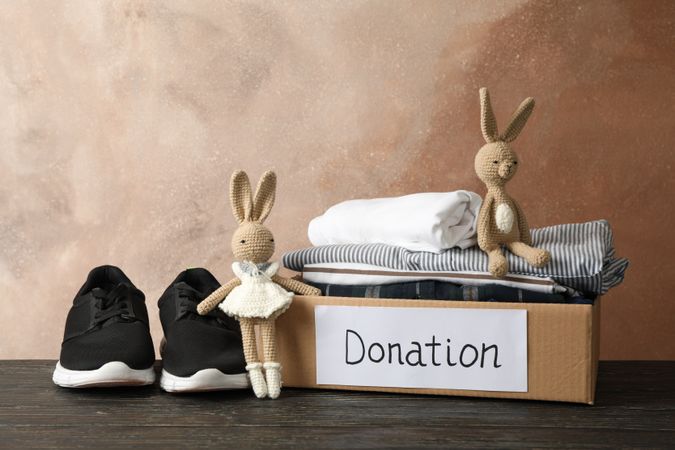Donation box with clothes and toys on wooden table