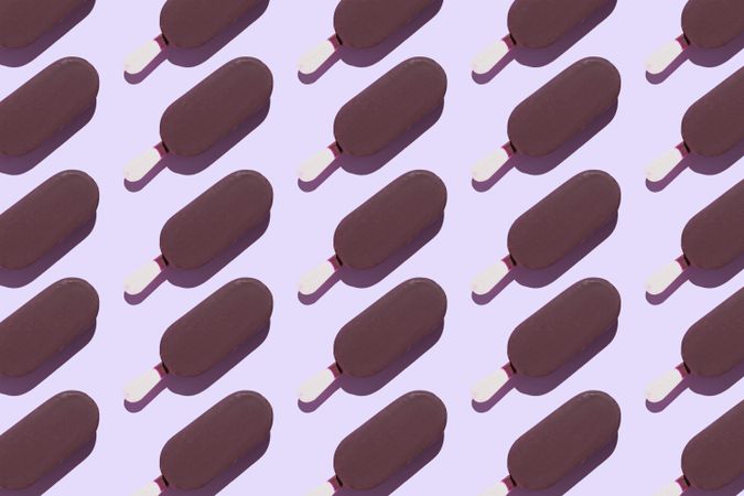 Multiple chocolate popsicles in diagonal rows on lavender background