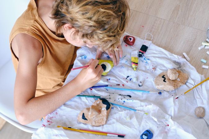 Child painting stone with aquarelle at home