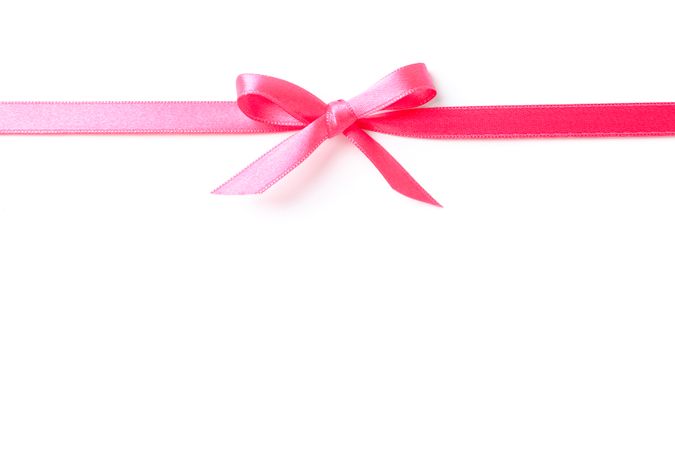 Pink ribbon with bow isolated on plain background. Gift concept