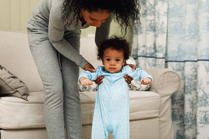 Baby boy standing with mother’s help