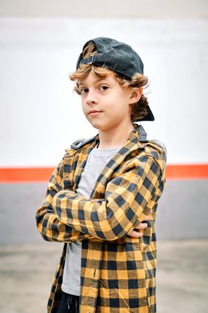 Child standing on street with crossed arms