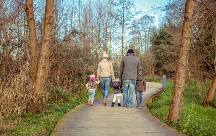Parents and children walking along forest path together