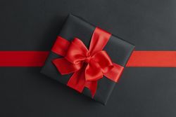 Gift box and red ribbon on dark background