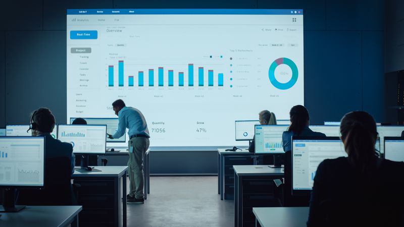 Data Analysts Work in a Dimly Lit Room, Examining Real-time Analytics on Individual Monitors.