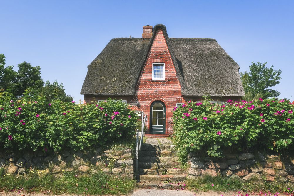 Red brick house with lush flower bushes