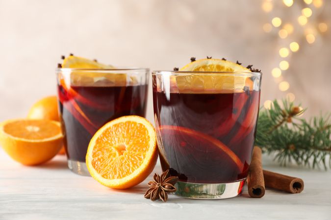 Glasses of tasty mulled wine with orange on wooden background, space for text