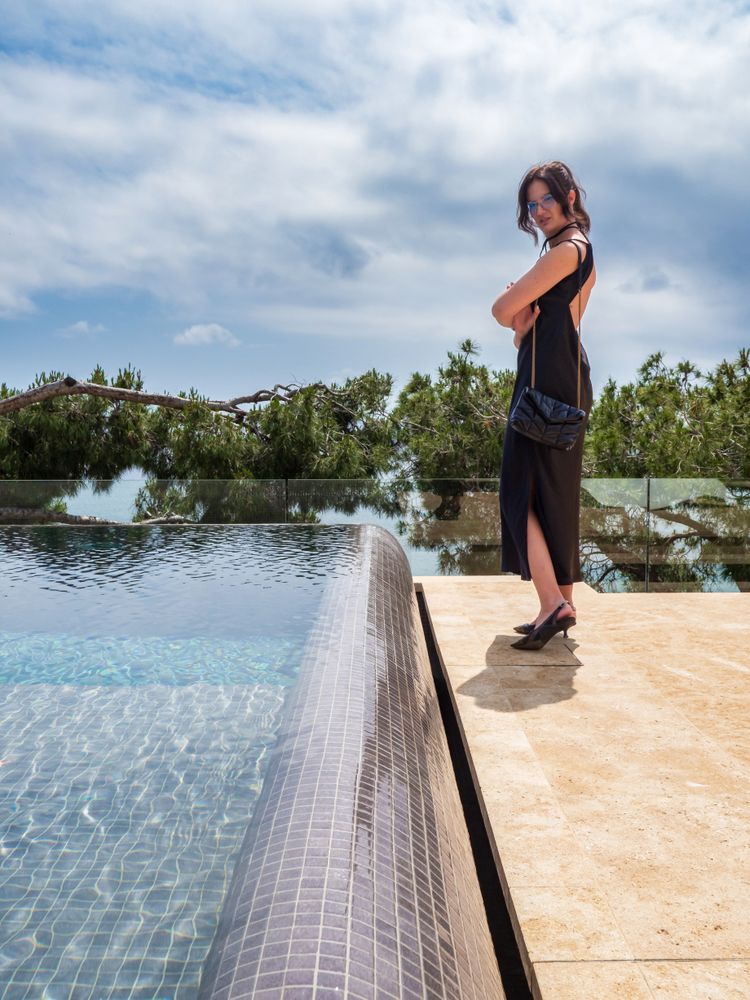 Woman in a dress elegantly poses near the pool at a luxurious villa
