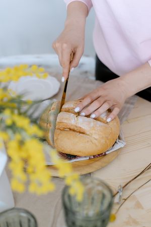 Cropped image of person slicing a loaf of bread