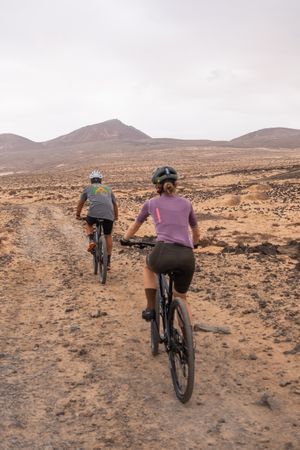 Back of man and woman biking on rugged terrain