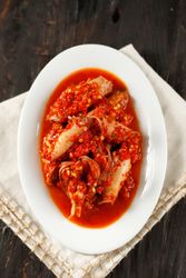 Spicy salted squid dish on wooden table, vertical