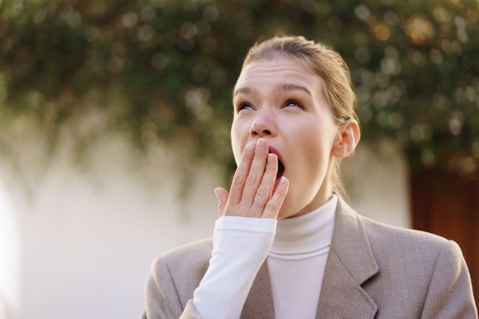 Stressed Businesswoman Yawning Outdoors  Capturing a Moment of Fatigue and Overwork