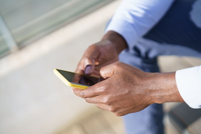 Close up of Black man holding a yellow phone
