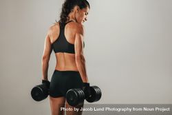 Back of beautiful woman holding dumbbells 0gXLW8