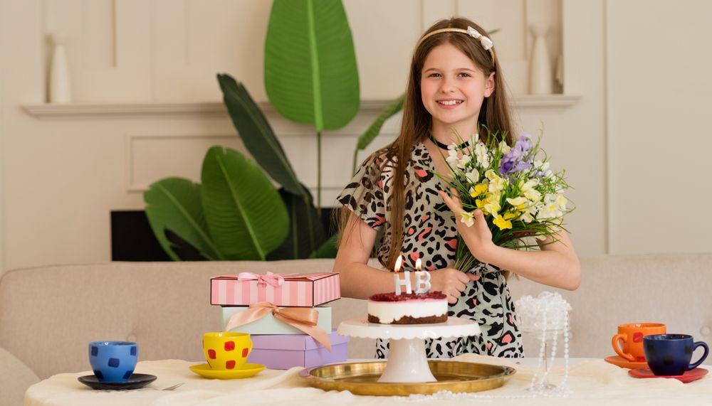 Girl enjoying birthday with flowers, cake and presents