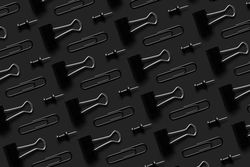 Binder clips and tacks on a dark background