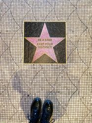 Floor sign resembling a Hollywood star asking for social distancing