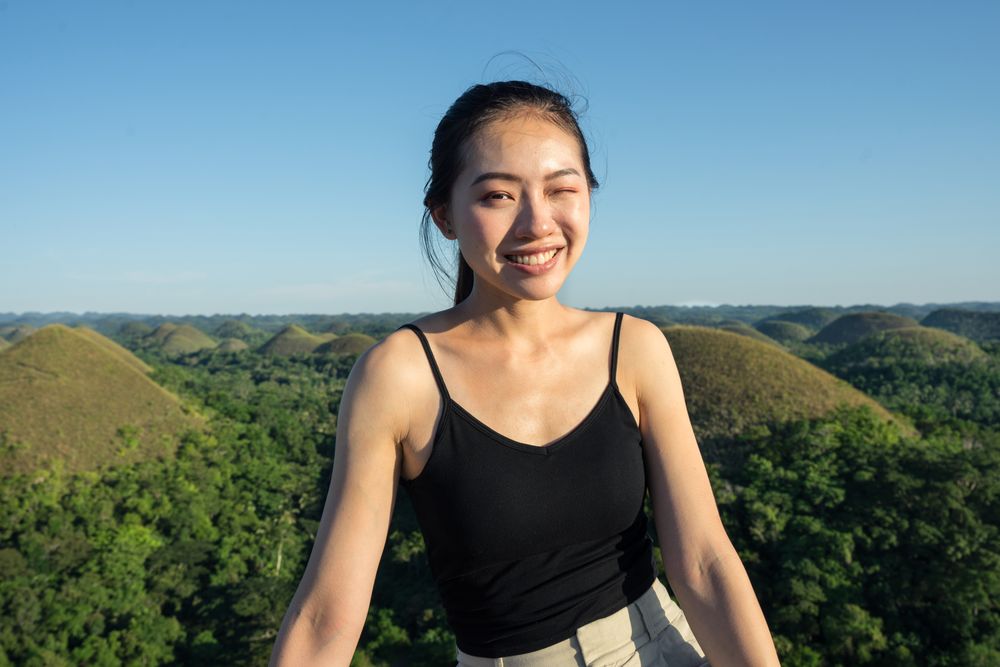 Happy woman standing on observation deck on hill