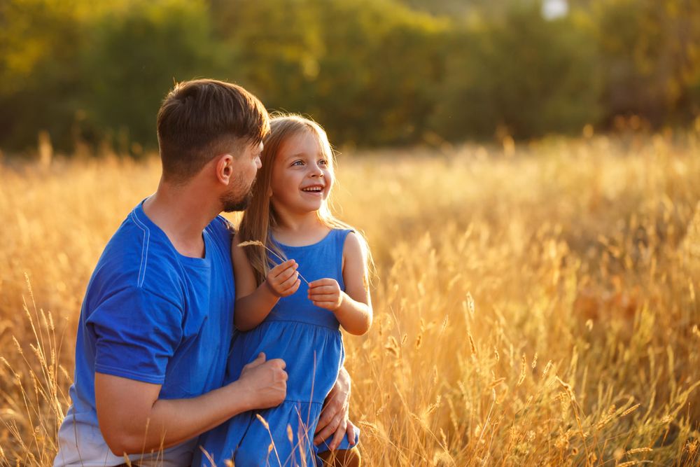 Dad and daughter playing in field of long grass