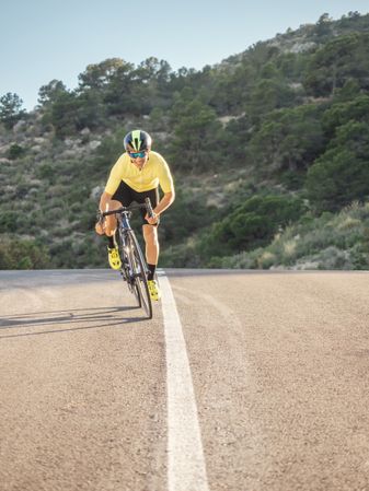 healthy man riding a bicycle on a mountain road in a sunny day