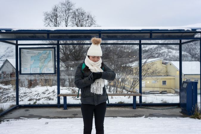Asian woman waiting for bus in snowy outdoors