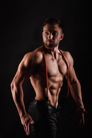 Bodybuilder practicing side poses ahead of competition in dark studio