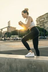 Athletic woman doing box jumps or step-up exercises during an outdoor HIIT workout