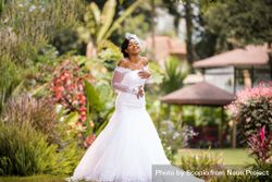 Smiling Black woman posing in wedding dress in the park 4dMoAb