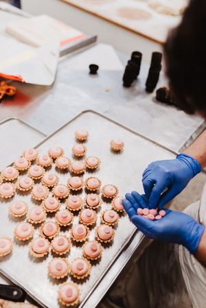 Anonymous baker decorating small cakes