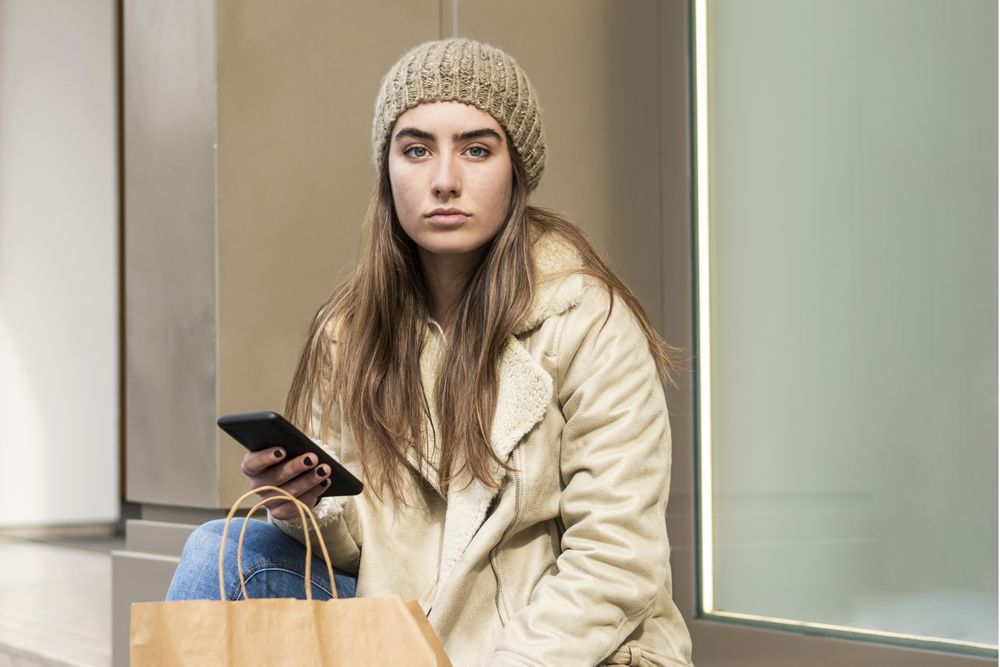 Female sitting outdoors while using a phone