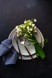 Top view of table setting for spring dinner with flowers on grey plate with space for text