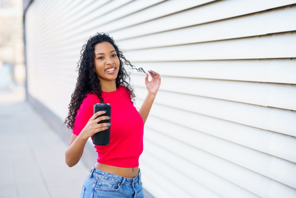 A Young Woman Enjoying a Lovely and Sunny Day While Using Her Smartphone and Smiling