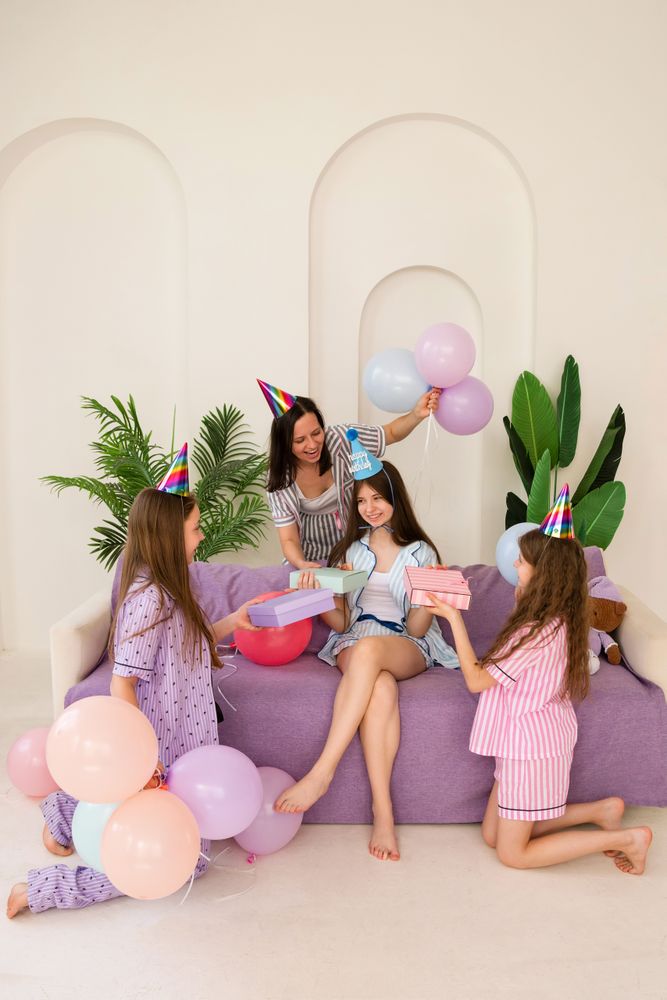 Family birthday celebration with mother and three daughters sharing gifts