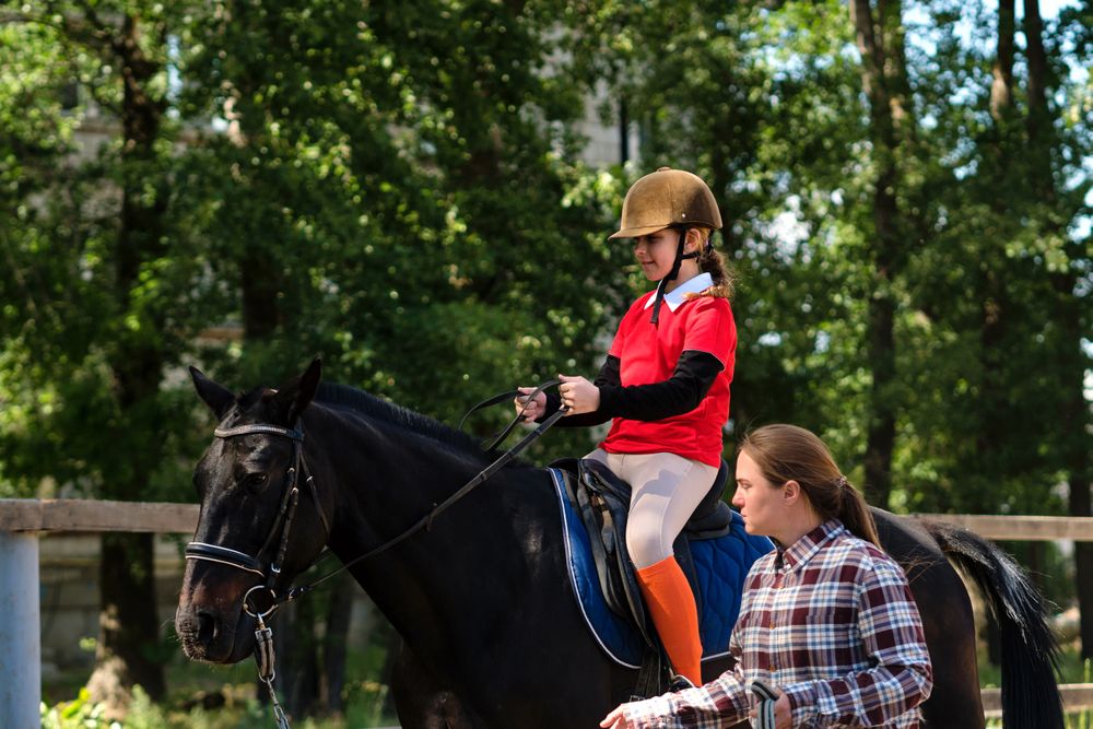 Young rider focuses on handling reins with instructor.