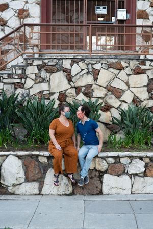 Loving couple sitting on stone wall looking at each other and smiling