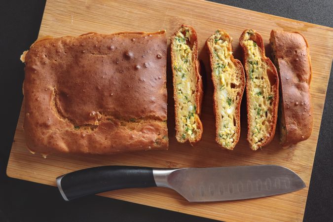 Onion pie is on wooden board with knife