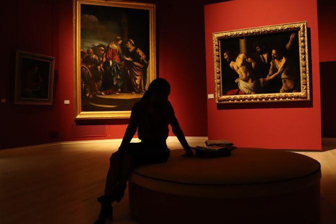 Silhouette of woman sitting on round couch in a museum