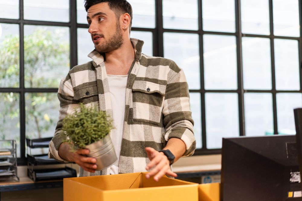 Young man in office putting his possessions in a box