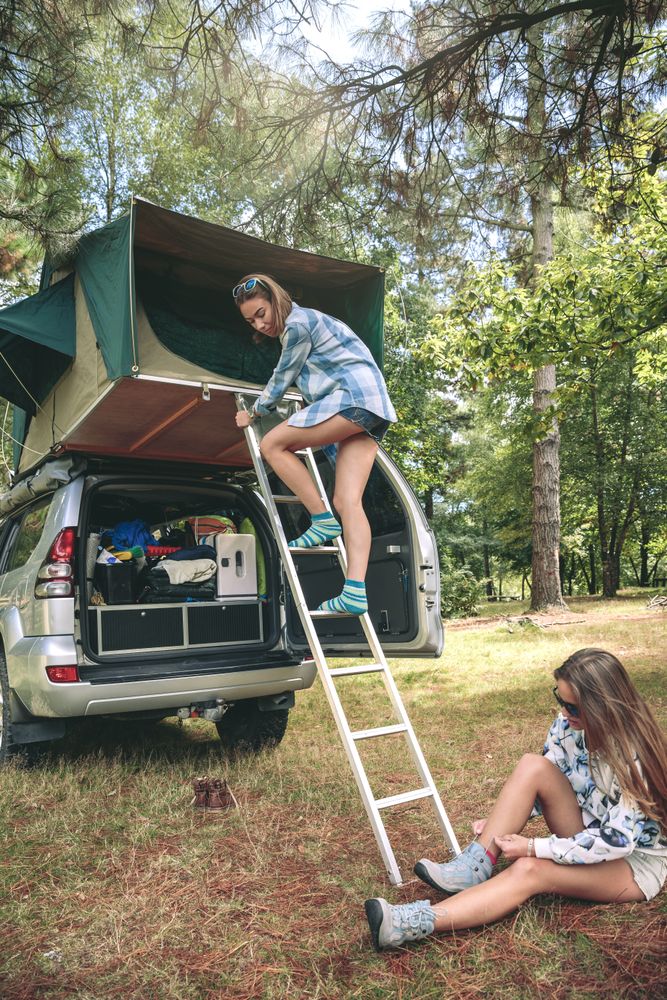 Woman ascending ladder to tent over car