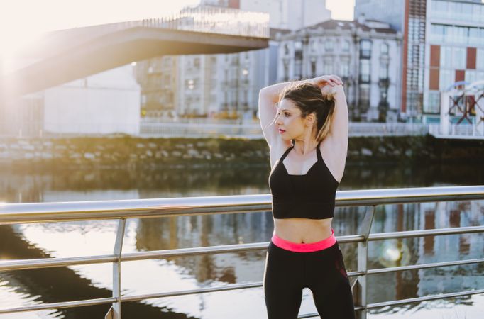 Woman stretching on embankment near water