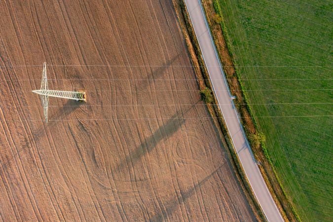 Aerial view with electricity pylon between agricultural fields