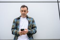 Cheerful man with smartphone looking at screen