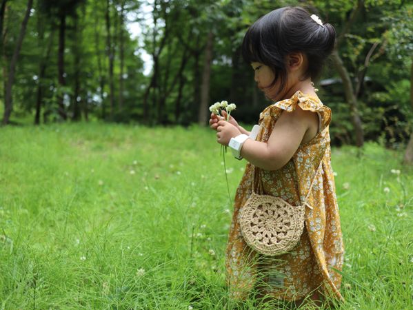 Side view of young girl in brown dress holding flower