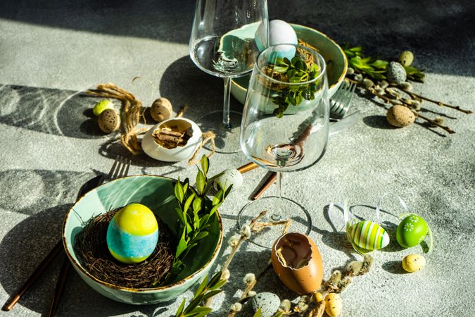 Easter table setting with glassware, teal bowl with decorative egg in nest